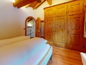 Habitació amb un llit, un armari de fusta i una escala que porta a una altra zona.