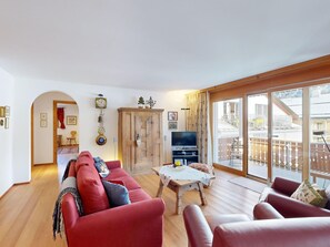 Ein geräumiges Wohnzimmer mit einem roten Sofagarnitur, einer Holzkommode und einem Fernseher.