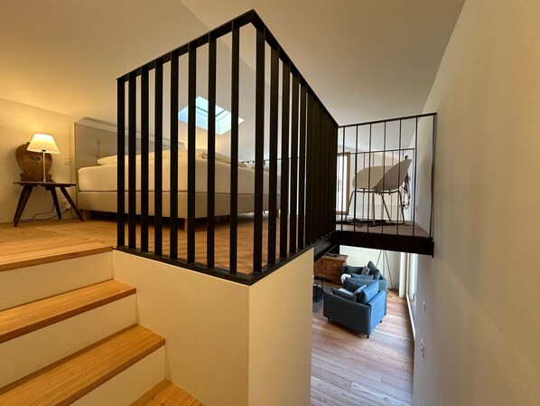 A staircase with wooden steps leading to a bedroom with a bed and a nightstand.