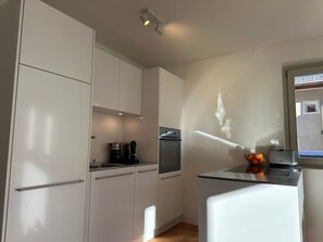 A modern kitchen with white cabinets, a built-in oven, and a coffee machine. - Chesa Unica - Terrassa mit Wellness by Interhome (Zuoz)