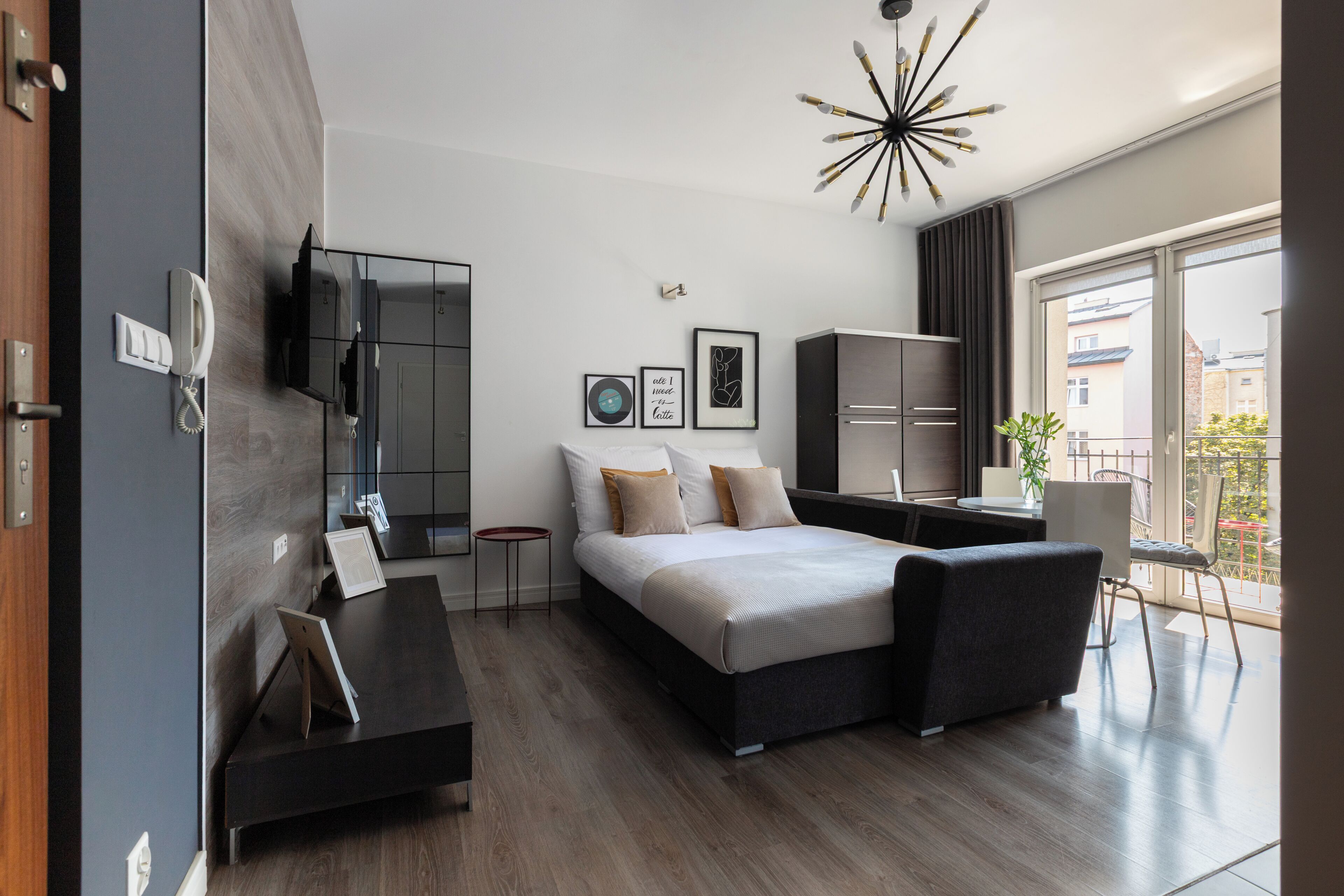 Un dormitorio moderno con cama, mesitas de noche, armario, televisor y balcón con vistas.