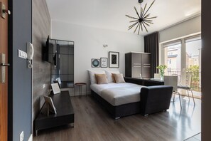 A modern bedroom with a bed, bedside tables, a wardrobe, a TV, and a balcony with a view. - Native Apartments Morawskiego 12 (Kraków)