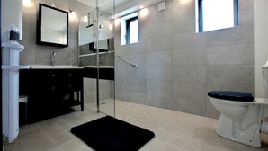 Et moderne badeværelse med en glasbrusekabine, toilet og håndvask.