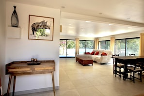 A spacious living area with a white sofa, a dining table, and a wooden side table with a tray.