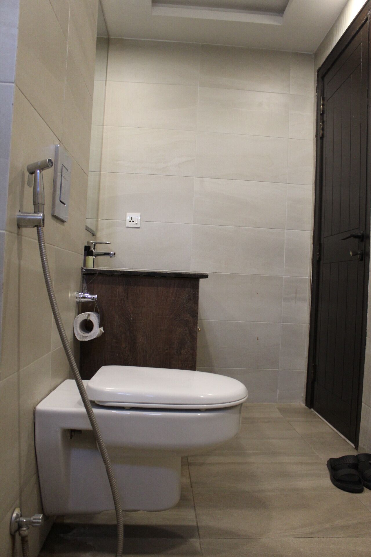 Un baño pequeño con inodoro, ducha y un mueble de madera oscura.
