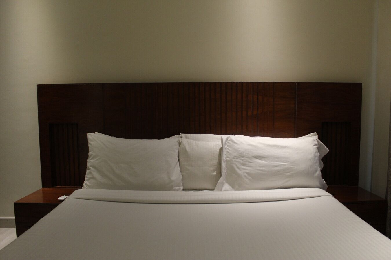 A bed with a wooden headboard, white bedding, and two bedside tables.