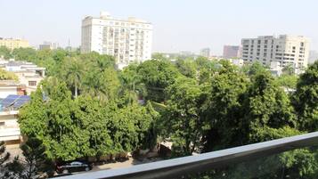 A residential area with multi-story buildings, dense greenery, and a clear sky.