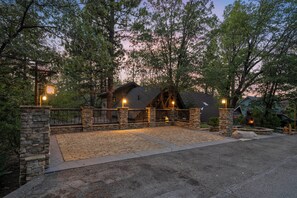 A stone-walled outdoor area with a paved walkway leading to a building with a sloped roof. - Disney Imagineer-Built Chalet Near the slopes | Fire Pit, Trails | Hot Tub (Big Bear Lake)