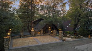 A house with a stone entrance, a paved driveway, and a bear statue. - Disney Imagineer-Built Cabin, Pet Friendly, Fire Pit, Walk to Town Trails (Big Bear Lake)