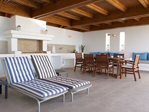 A sunlit patio area with a dining table, chairs, and a cushioned seating area. - Haus in Vlycha Beach mit Infinity-Pool by Interhome (Pefki)