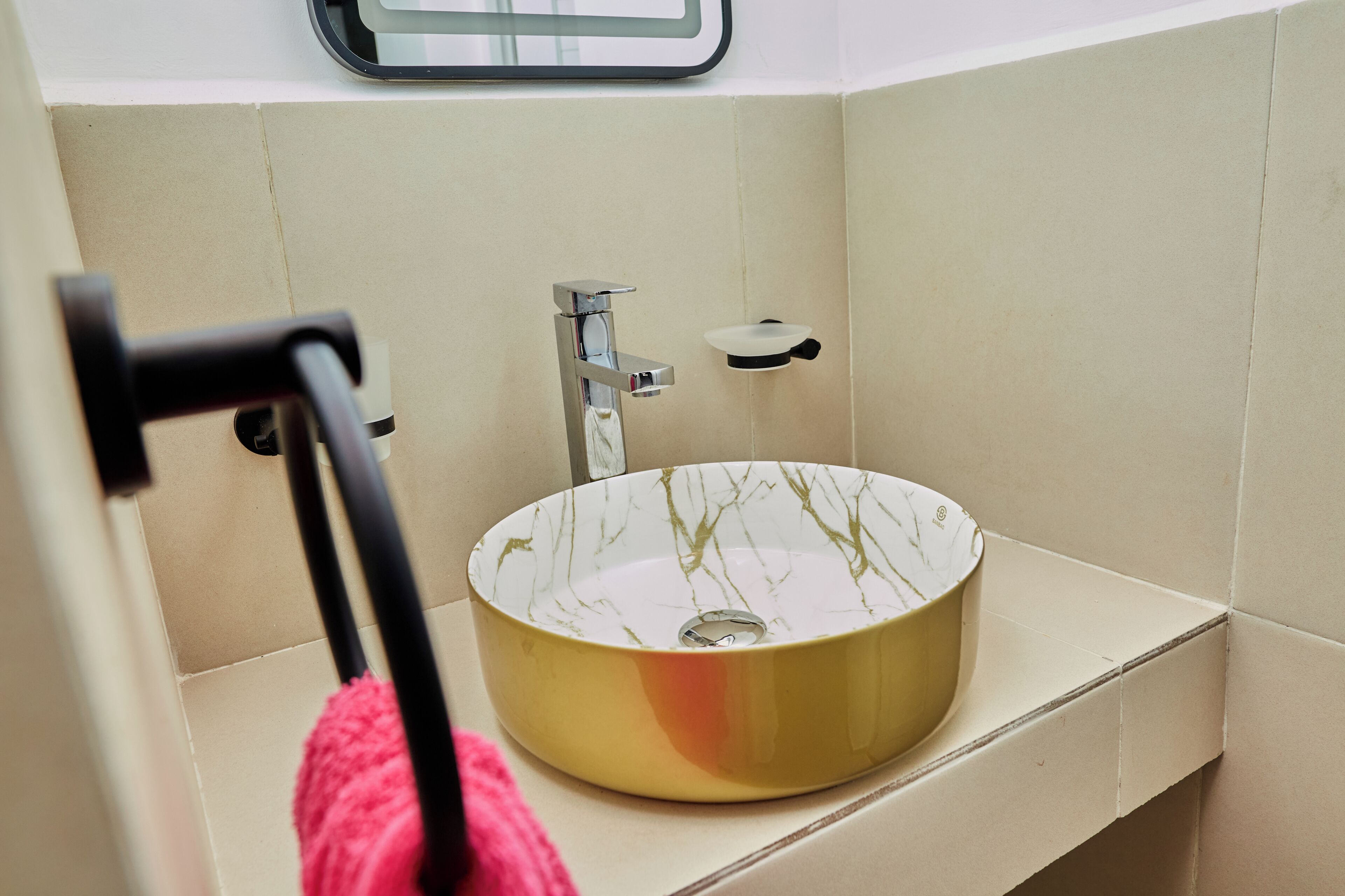 A bathroom with a round sink, a towel rack, and a mirror.