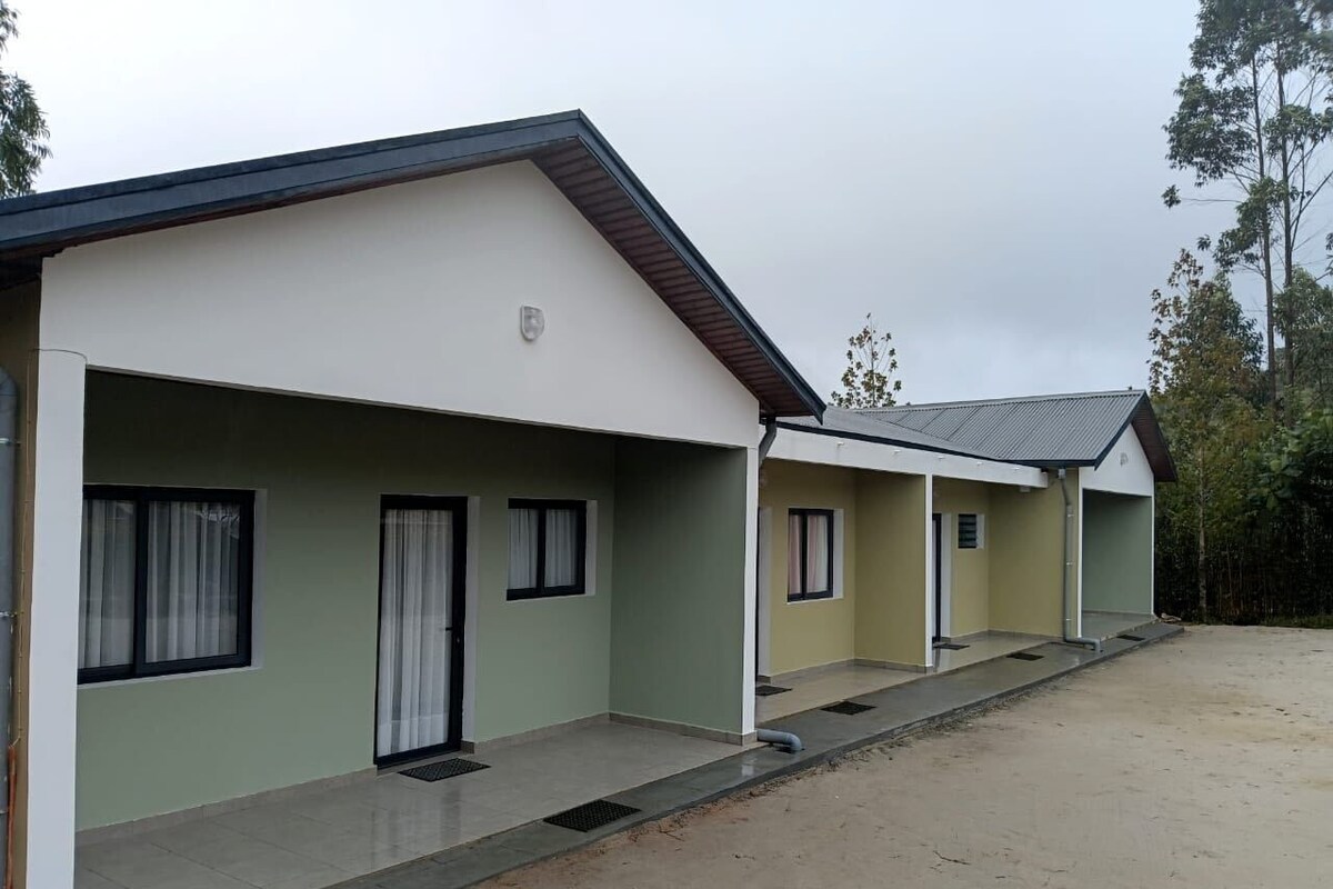 A row of single-story buildings with a flat roof, each with a door and a window.