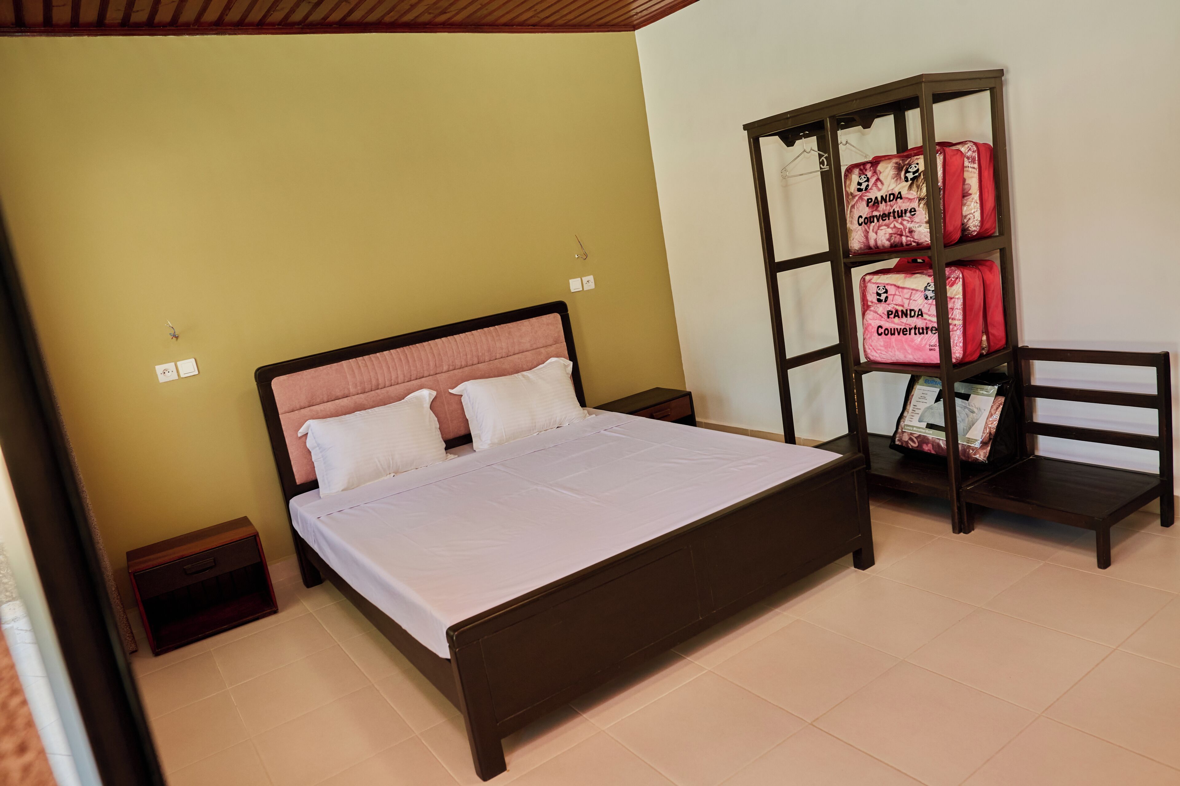 A bedroom with a bed, a nightstand, a wardrobe, and a chair.