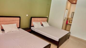 A hotel room with two beds, a wooden ceiling, and a bathroom visible through an open door.