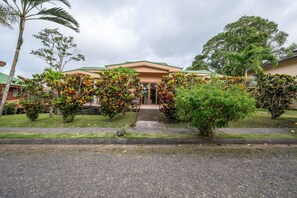 A building with a flat roof, surrounded by well-maintained greenery and a paved entrance area. - Buena Vista Mountain Nest |2BR | Lake Views | Pool (Tilarán)