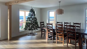 Ein Essbereich mit Holztisch und -stühlen, einem Weihnachtsbaum und großen Fenstern.