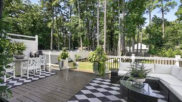 A deck with a checkered floor, white furniture, and potted plants.