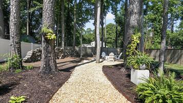 A gravel pathway leading through a wooded area with trees and a wooden fence.