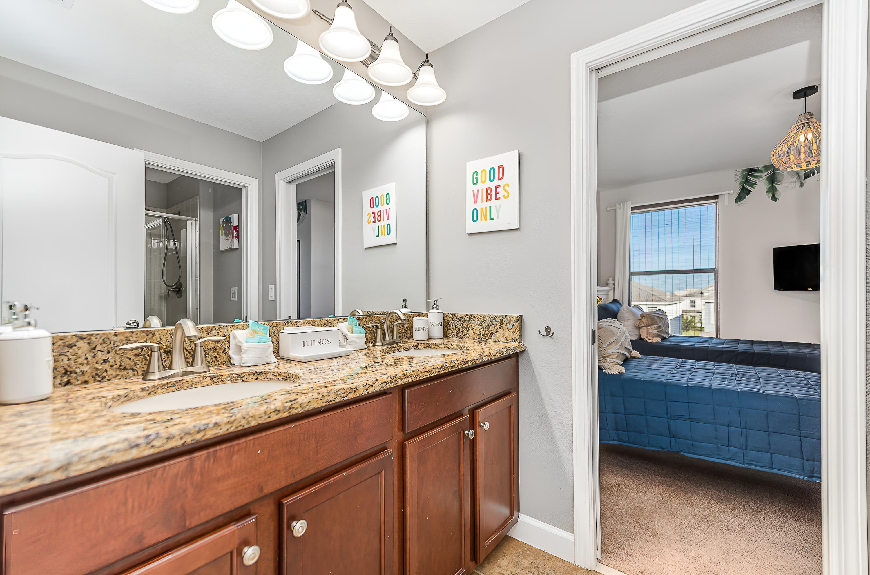 A bathroom with a granite countertop, a mirror, and a shower.