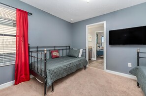 Ein Schlafzimmer mit einem Etagenbett, einem Einzelbett, einem Fernseher und einer Tür zu einem anderen Raum.