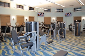 A gym with various exercise machines, including treadmills and weight stations, and multiple television screens mounted on the walls. - Epic Villa By Disney Theater Game Room Pool Spa (Davenport)