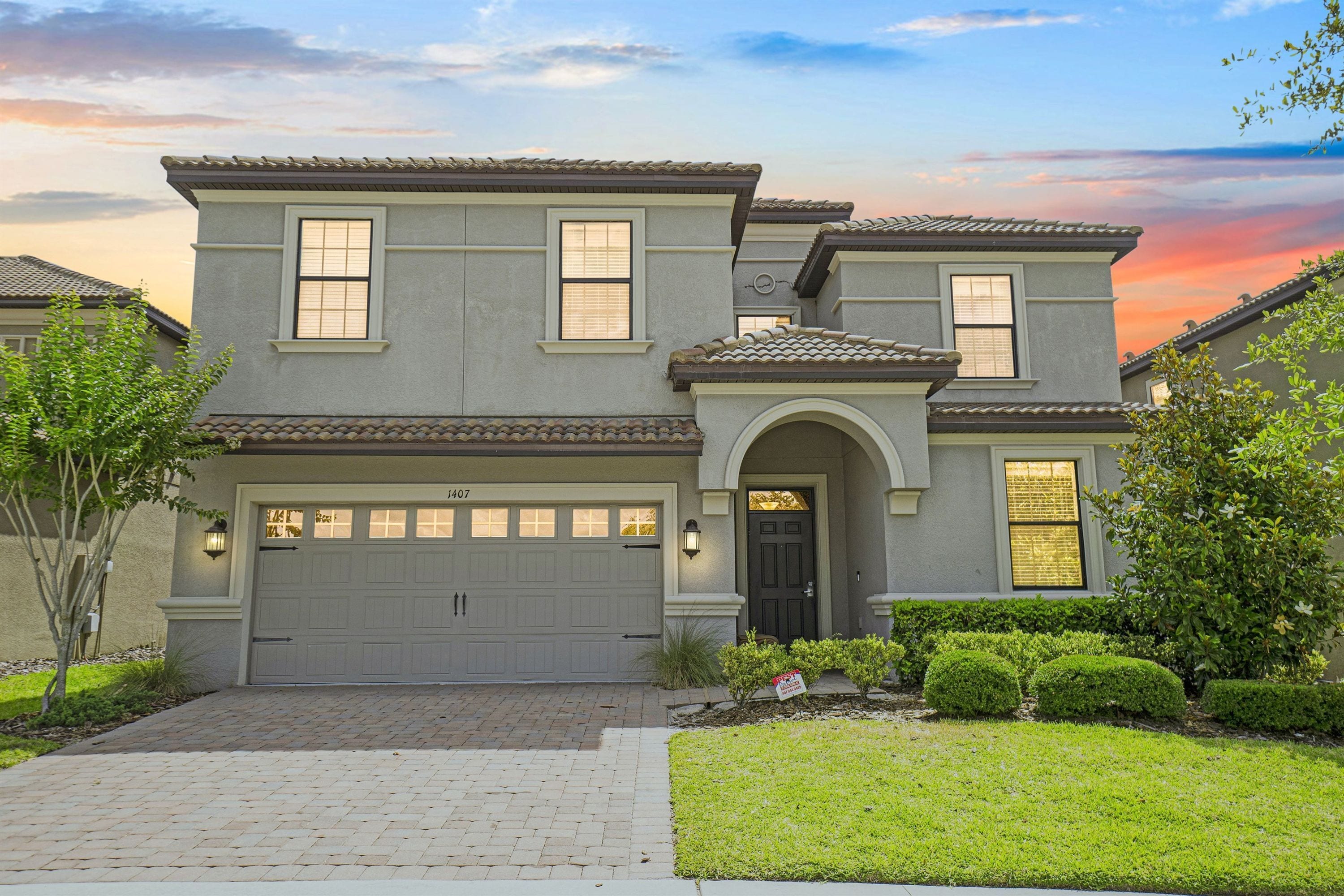 A two-story house with a garage, a front entrance with an arch, and a well-maintained lawn.