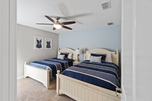 A bedroom with two beds, a ceiling fan, and a light fixture. - Rolling Skies Poolside Cinema Free BBQ Near Disney (Davenport)