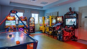 An arcade room with various gaming machines, including racing and shooting games. - Rolling Skies Poolside Cinema Free BBQ Near Disney (Davenport)