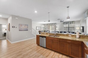 A modern kitchen with granite countertops, stainless steel appliances, and wooden cabinets. - Rolling Skies Poolside Cinema Free BBQ Near Disney (Davenport)