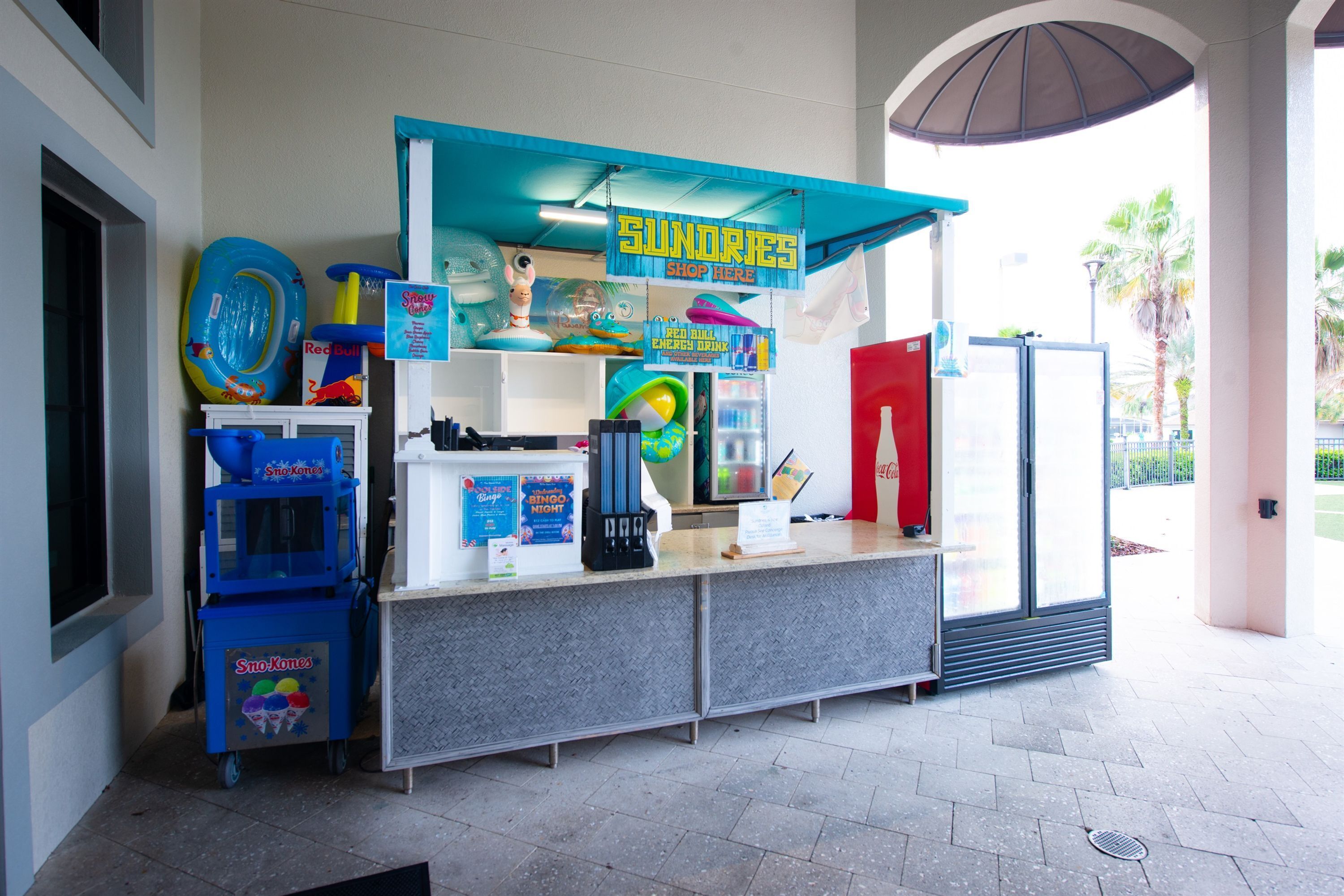 A kiosk with a blue awning, vending machines, and various items for sale.