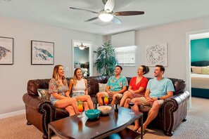 Ein Wohnzimmer mit einer braunen Ledersofa, einem Couchtisch mit Getränken und Kunstwerken an den Wänden.