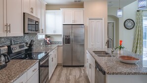 A modern kitchen with stainless steel appliances, granite countertops, and white cabinetry. - Magical Retreat - Near Disney Heated Pool Spa (Davenport)