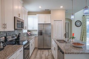 A modern kitchen with stainless steel appliances, granite countertops, and white cabinetry. - Magical Retreat - Near Disney Heated Pool Spa (Davenport)