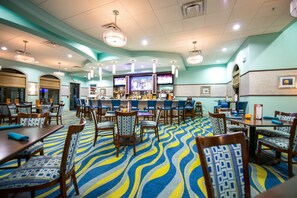 A hotel lobby with a bar area, multiple seating arrangements, and a patterned carpet. - Magical Retreat - Near Disney Heated Pool Spa (Davenport)