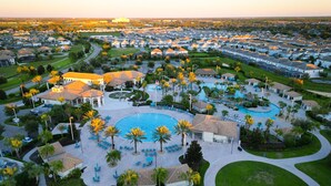 A residential area with a central swimming pool surrounded by palm trees and lounge chairs. - Magical Retreat - Near Disney Heated Pool Spa (Davenport)