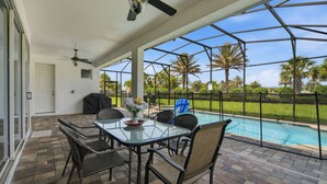 Un patio coperto con piscina, mobili da esterno e ventilatore a soffitto.