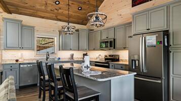 A modern kitchen with a central island, stainless steel appliances, and a wooden ceiling.