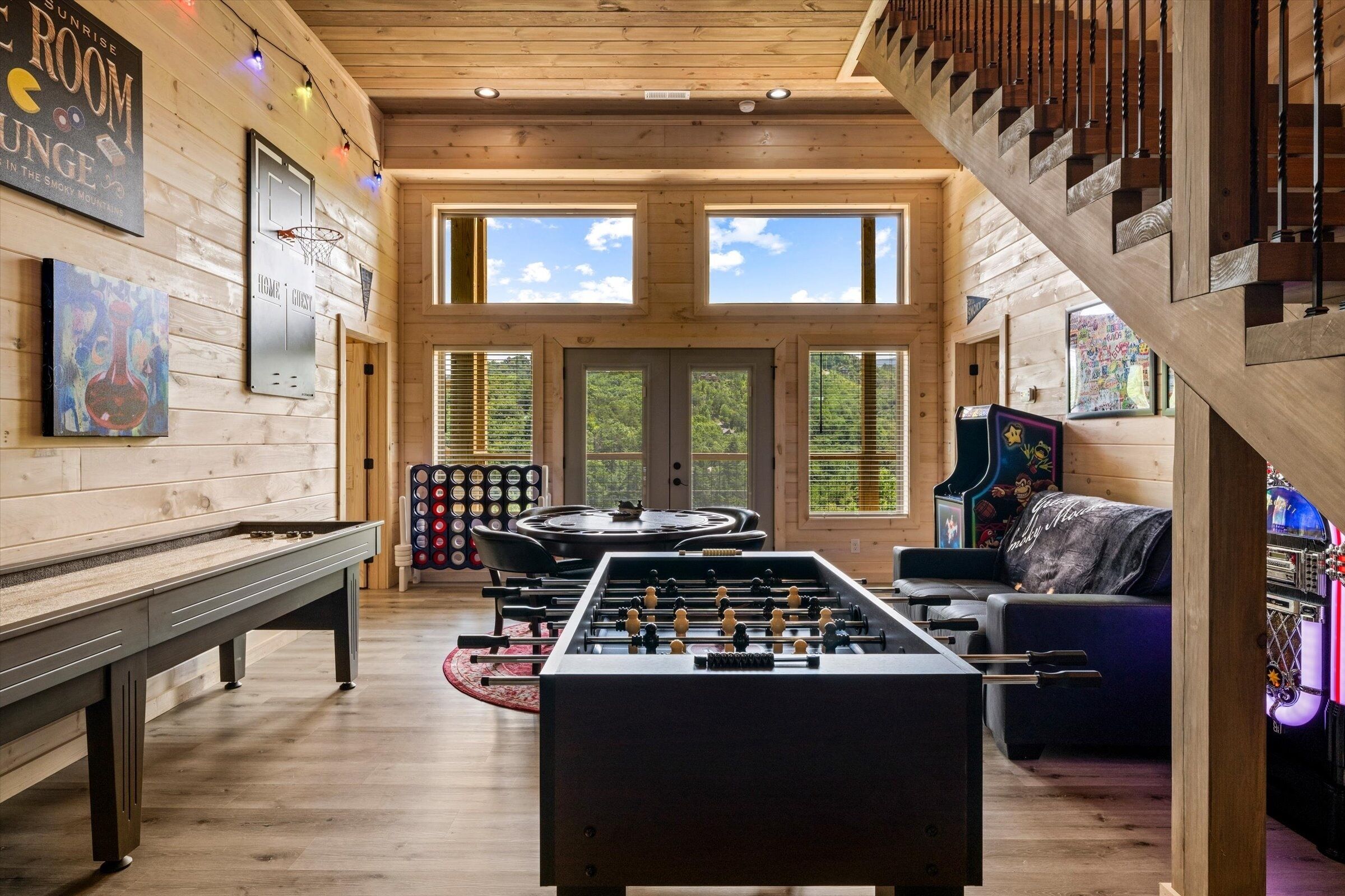 A cozy room with a foosball table, a pool table, and a piano.