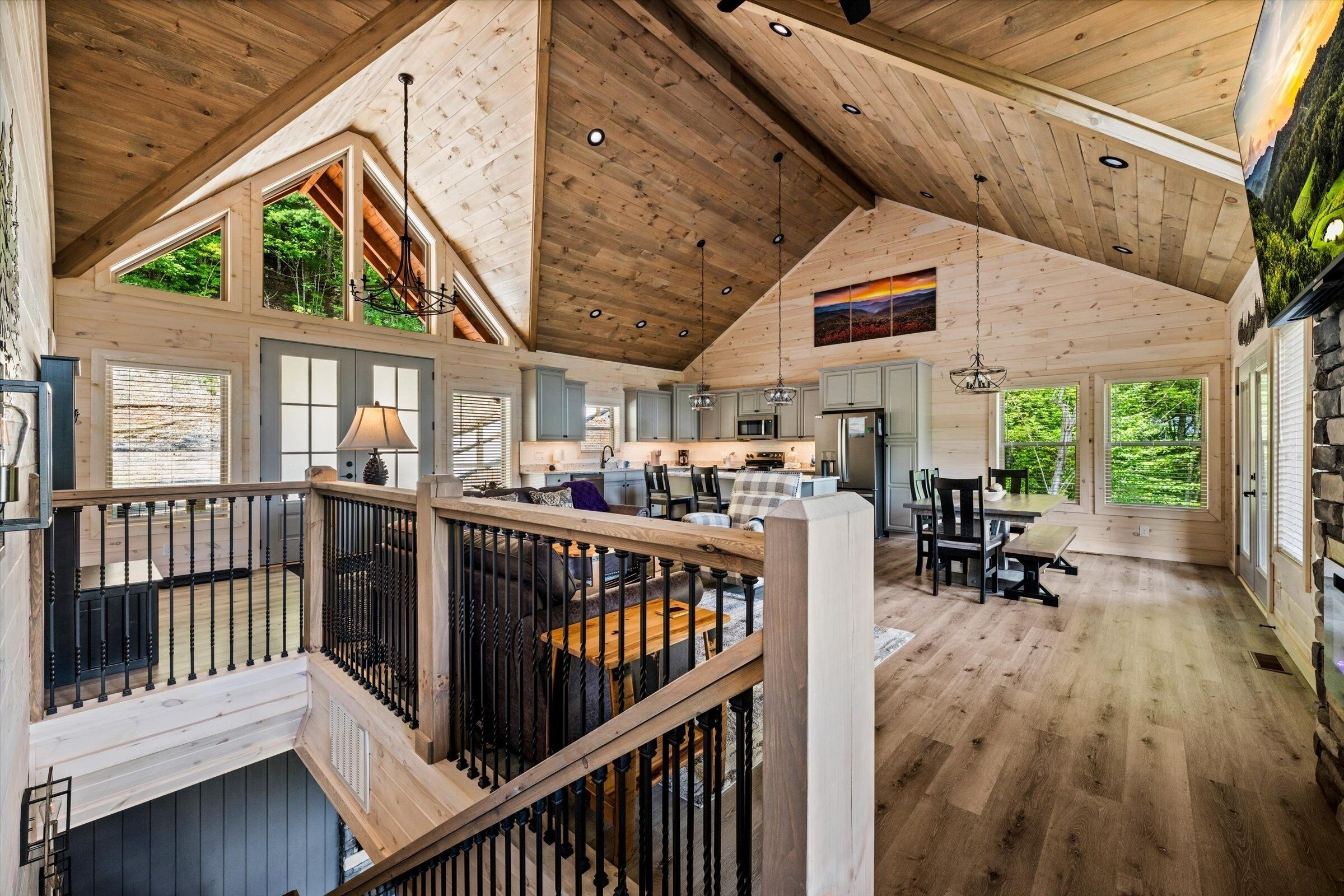 A spacious interior with a high ceiling, wooden beams, and large windows offering views of the outdoors.