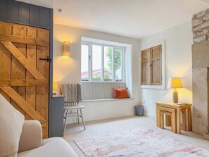 A cozy room with a large wooden door, a window with a view, a small table with a lamp, and a bench with cushions. - Peak Dreams (Buxton)