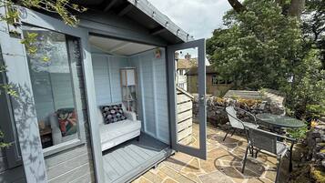 Een modern huis met een ingebouwde zithoek, een stenen terras en tuinmeubilair.