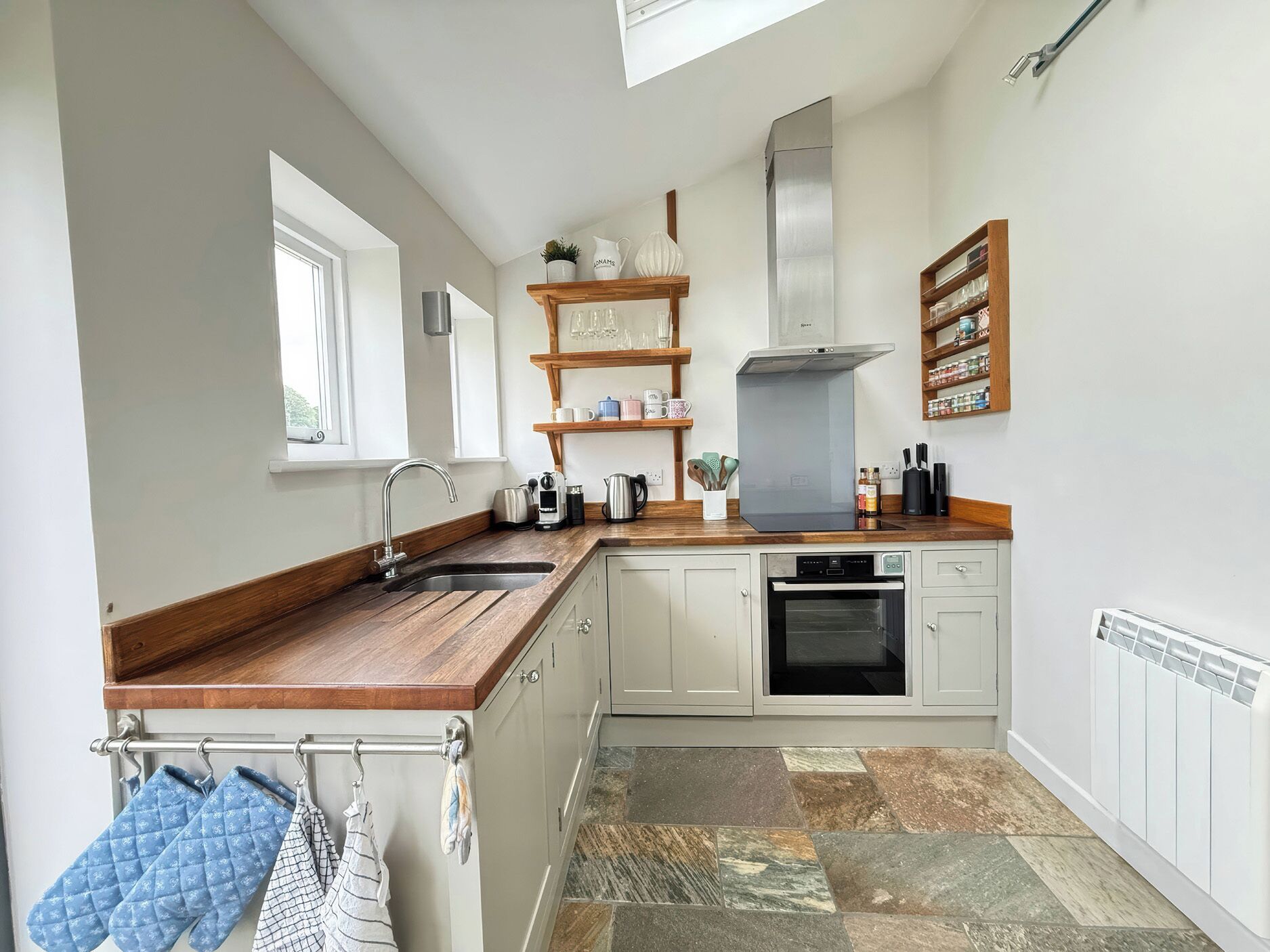 A kitchen with a built-in oven, a sink, and a window.