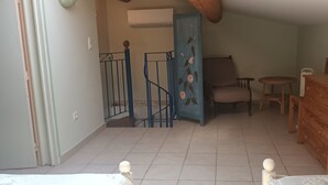 Una habitación con una cama, un aparador de madera, una silla, una mesita y una puerta azul.