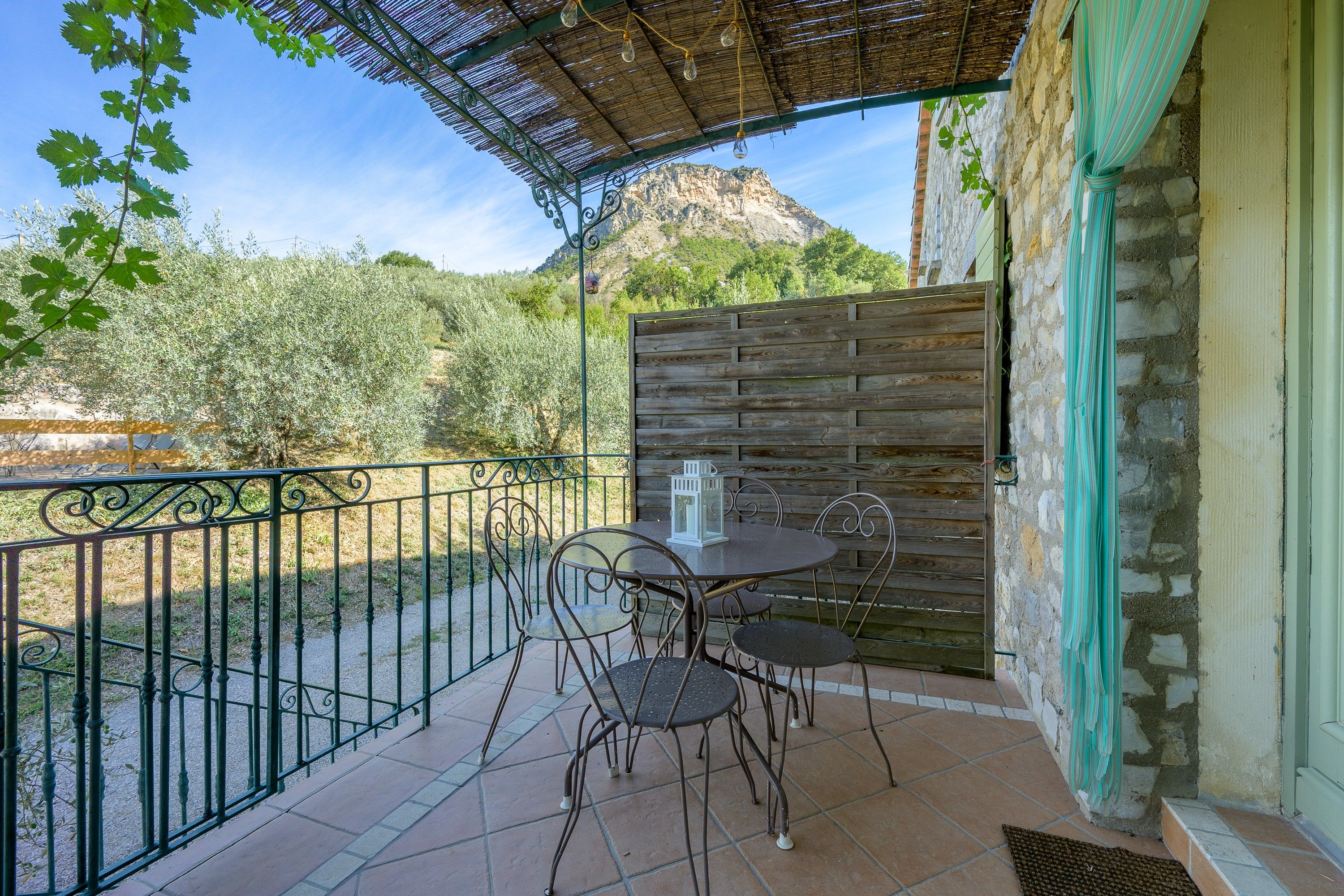 An outdoor patio with a table and chairs, a wooden fence, and a mountain in the background.