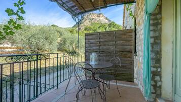 An outdoor patio with a table and chairs, a wooden fence, and a mountain in the background.