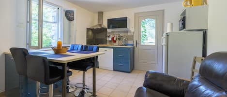Una cocina compacta con zona de comedor, refrigerador y microondas.