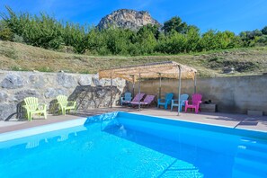 Una piscina amb mur de pedra i formació rocosa al fons.