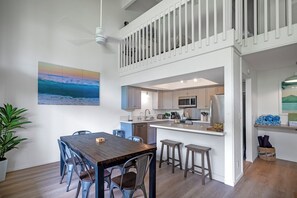 Eine moderne Küche mit einer zentralen Kochinsel, Edelstahlgeräten und einem Essbereich mit Holztisch und Metallstühlen.