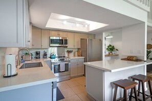 A modern kitchen with a central island, stainless steel appliances, and a skylight. - Elegant and spacious, walk to shopping, dining, Anini beach (Princeville)