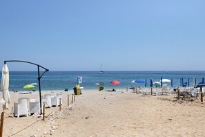 A beach with rows of white lounge chairs and umbrellas, a clear sky, and the sea in the background. - Terrazze Arenella Guest House: Sea View, Wi-Fi, Air Conditioning (Palermo)